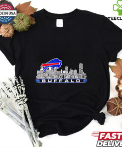 For a **Buffalo Bills shirt featuring Thurman Thomas, Bruce Smith, Jim Kelly, and a city skyline**, here's a detailed design concept: **Design Elements**: - **Central Feature**: The **Buffalo Bills logo** in the center, prominently displayed in vibrant **Buffalo blue** and **red** with a metallic shine. It can be **3D-styled** to pop against the background. - **City Skyline**: A **detailed silhouette of Buffalo city skyline** (including recognizable buildings and landmarks) should be incorporated behind the logo. The skyline should be in shades of **grey or black** to ensure the focus remains on the logo and players. Adding a subtle glow or light effect could make the skyline feel more dynamic. - **Player Images**: - **Thurman Thomas**, **Bruce Smith**, and **Jim Kelly** should be included in **action poses**, either in a **side-by-side layout** or in a **triangular formation**. They should have a slightly **retro-style treatment**, capturing their iconic moments. Use an **artistic illustration** style rather than direct photos to keep the design cohesive and unique. - Each player’s **name and number** should be placed underneath their image (e.g., **Thurman Thomas #34**, **Bruce Smith #78**, **Jim Kelly #12**) in bold, **athletic-style font**. - **Text Elements**: - Across the top or bottom of the design, include the text **
