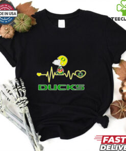Oregon Ducks x Snoopy Player Heartbeat Shirt, featuring a unique design that combines the Oregon Ducks logo and mascot with Snoopy in a fun, heartwarming graphic. Perfect for fans who love both the Ducks and the iconic Peanuts character, celebrating their passion for the team with a playful twist.