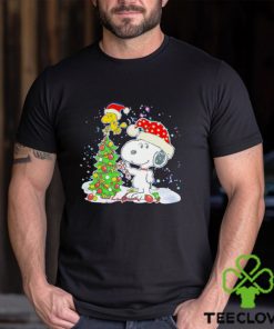 Snoopy and Woodstock wear Santa hats by the pine tree Christmas shirt